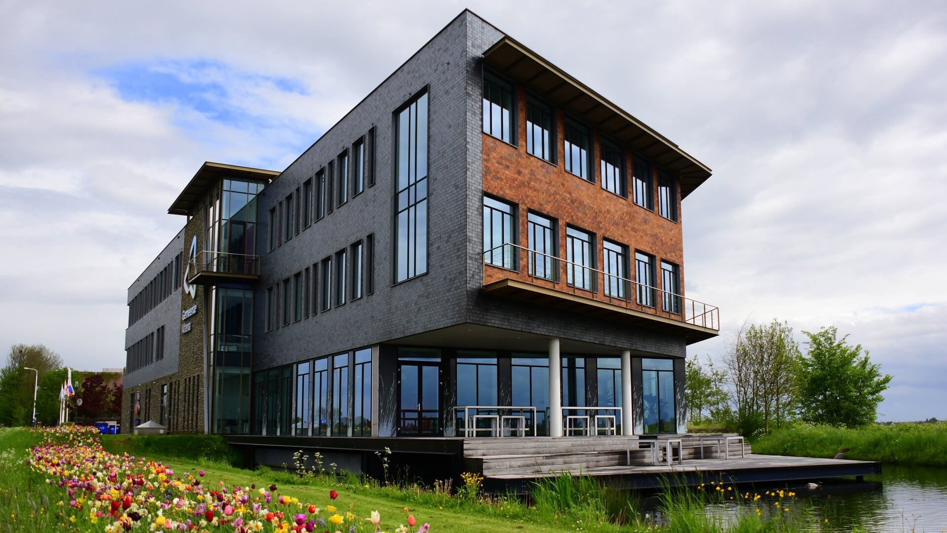 Modern kantoorpand van WebsitesAltena aan het water met tulpen in de Altena regio